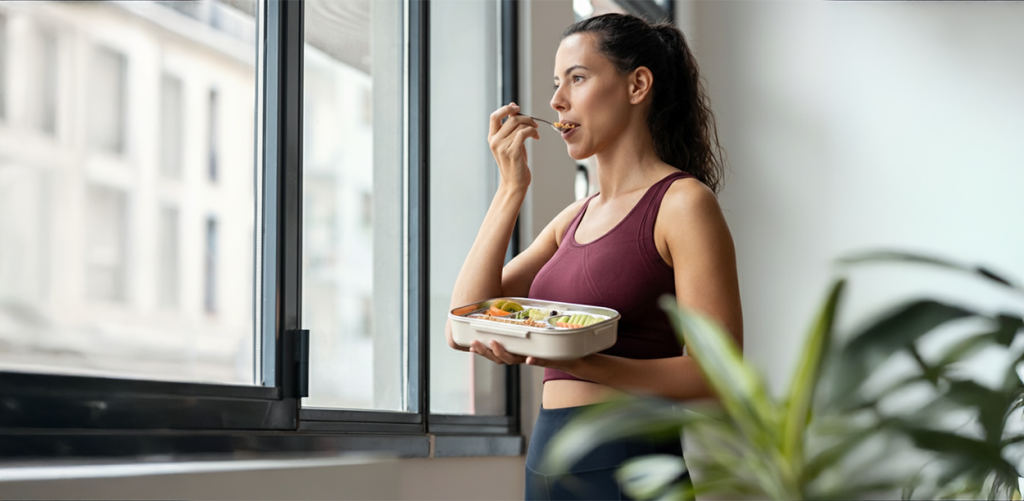 Woman eating a healthy home-packed meal from an Aurovaa bento box, promoting workday wellness, balanced nutrition, and an active lifestyle.